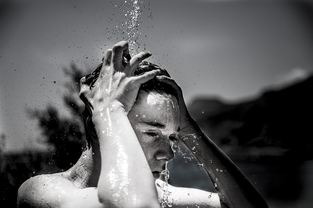 černobílá fotografie sprchujícího se chlapce ve venkovním prostředí
